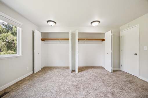 A room with white walls and carpeted floor with two closets.