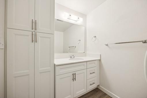 A white bathroom with a sink and a mirror.