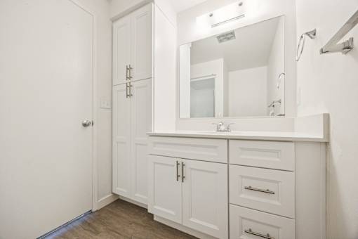 A white bathroom with a mirror and a cabinet.