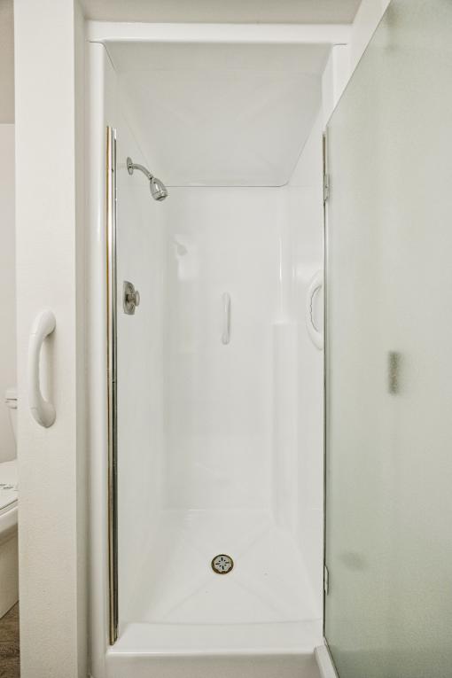 A white shower stall with a door and a shower head.
