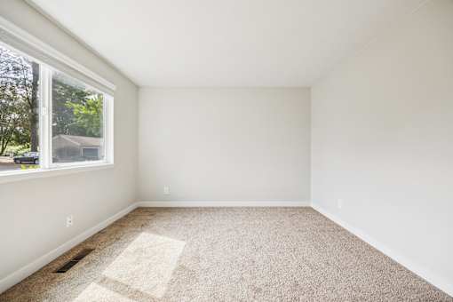 A room with a carpeted floor and a window.