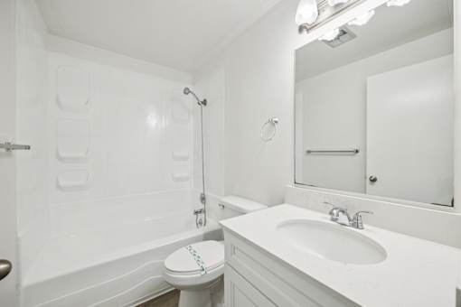 A white bathroom with a toilet, sink, and bathtub.