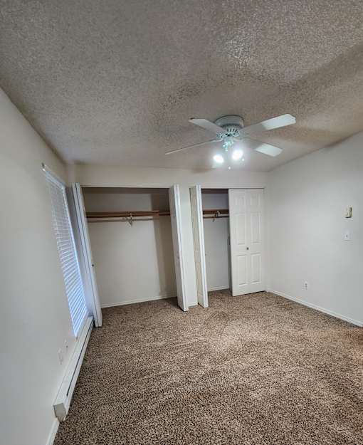 A room with a ceiling fan and carpeted floor.