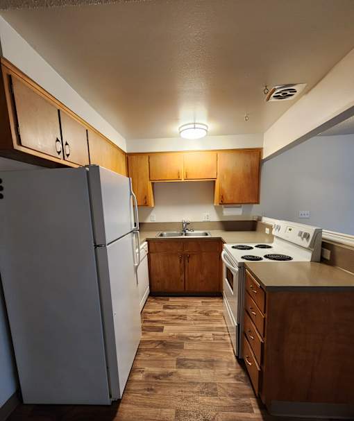 A kitchen with a white refrigerator and a white stove top oven.