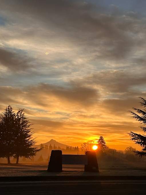 A beautiful sunset with a mountain in the background and a bench in the foreground.