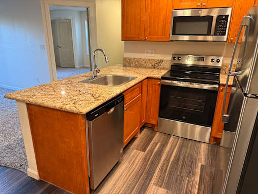 A kitchen with a granite countertop and stainless steel appliances.