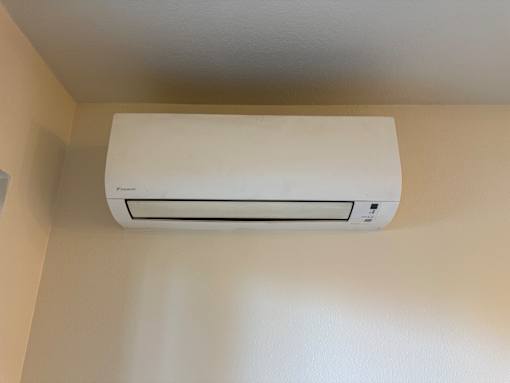 A white air conditioner is mounted on a white wall.