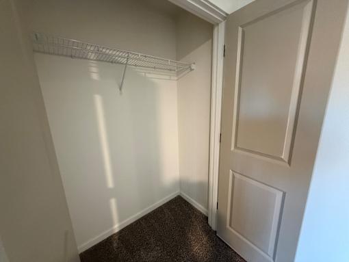 A white door is open to a hallway with a shelf.