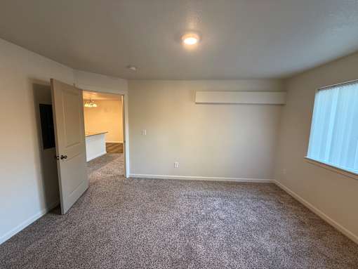 A room with a carpeted floor and a window with blinds.