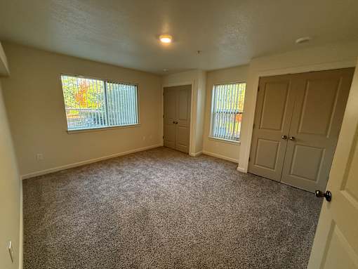 A room with carpeted floor and two doors.