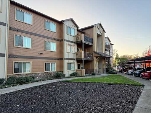 Apartment complex with a parking lot in front.
