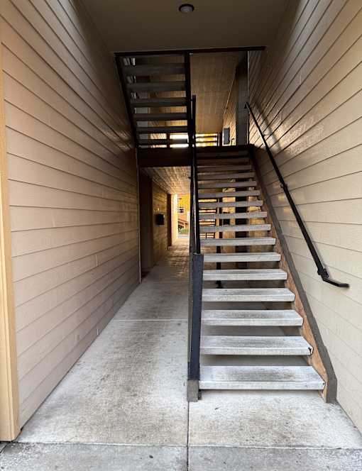 A staircase with a black railing and wooden steps.