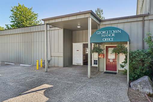 The Georgetown Manor Office is a small building with a red door and a green awning.