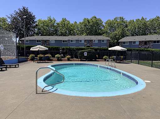 A small pool with a diving board in the middle of a concrete area.