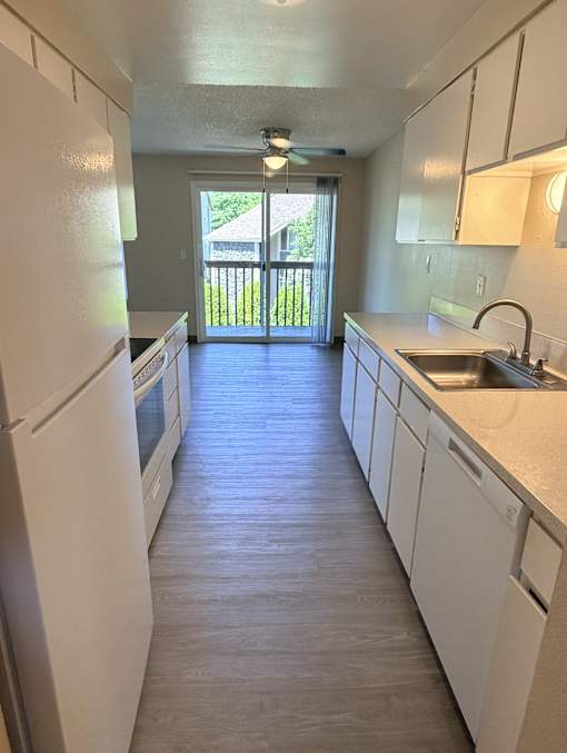 A kitchen with white appliances and cabinets.