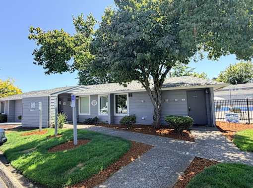 A house with a grey roof and a tree in front of it.