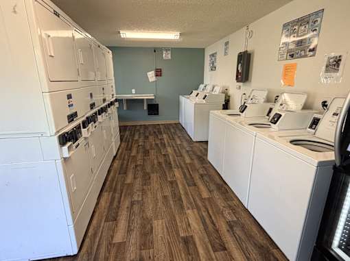 A laundromat with washers and dryers lined up.
