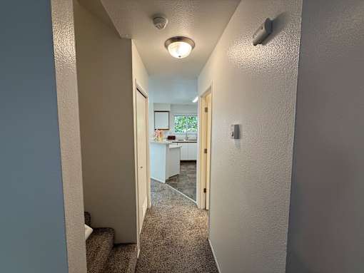 A hallway with a carpeted floor and a light on the ceiling.