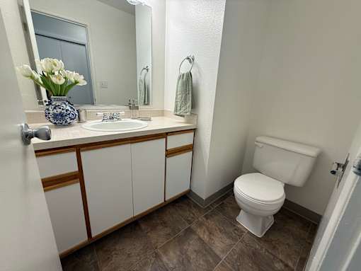 A white toilet sits in a bathroom next to a sink and a mirror.