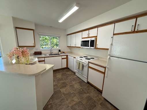 A kitchen with white cabinets and a tiled floor.