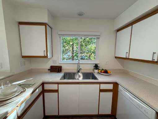 A kitchen with white cabinets and a window.