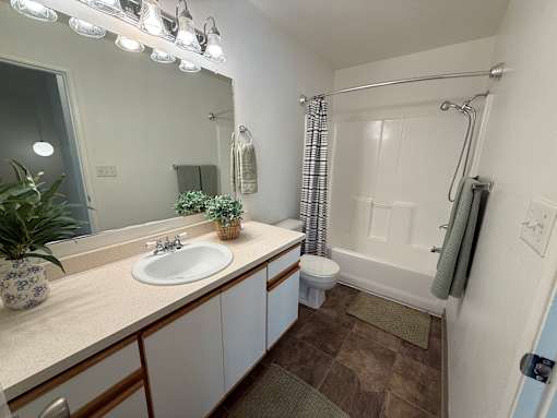 A bathroom with a sink, mirror, and shower.