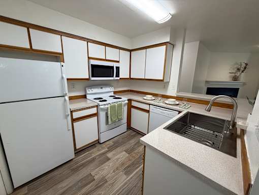 A kitchen with white appliances and wooden cabinets.