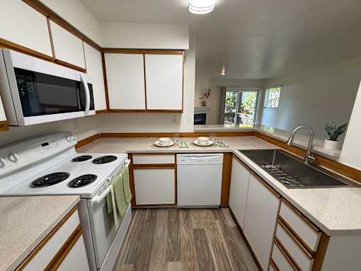 A kitchen with a stove top oven, microwave, dishwasher, and sink.