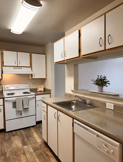 A kitchen with white appliances and wooden cabinets.