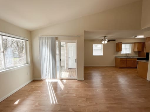 an empty living room with a doorway into a kitchen
