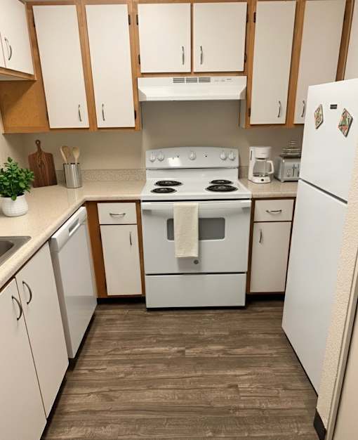 A white stove and refrigerator in a kitchen with wooden cabinets.