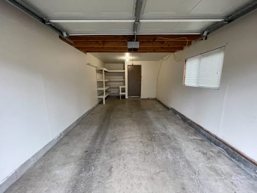 a basement with a concrete floor and a white wall with a ladder on the side of the