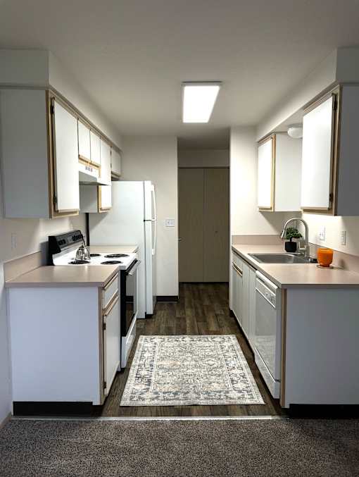 A kitchen with white cabinets and a rug on the floor.