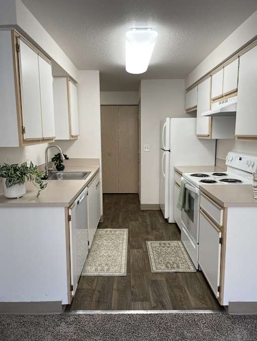 A kitchen with white appliances and cabinets.