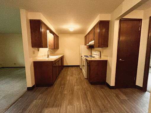 A kitchen with wooden floors and cabinets.