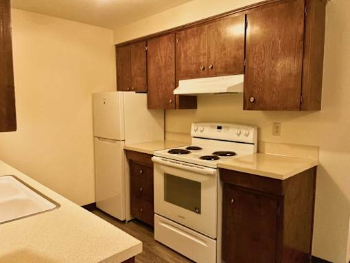 A kitchen with white appliances and brown cabinets.