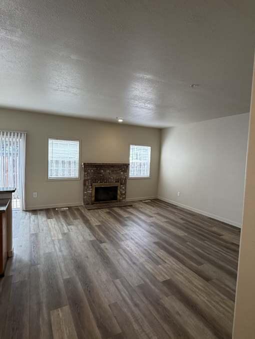 A room with a fireplace and wood flooring.