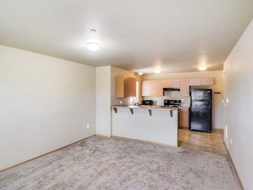 A kitchen area with a black fridge, white countertops, and a microwave.