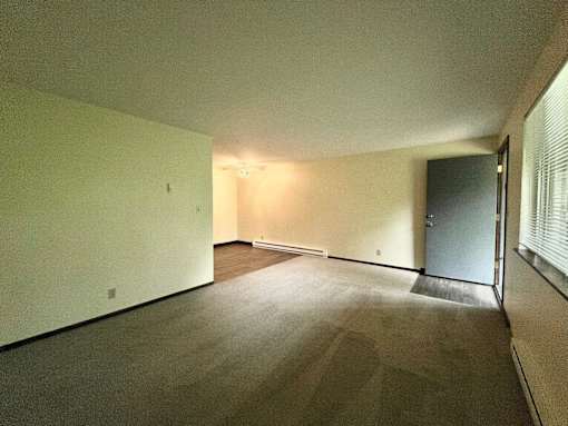 A room with a carpeted floor and a door on the right side.