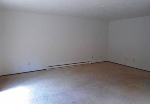 A large empty room with a carpeted floor and white walls.