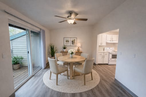 A dining room with a table set for two and a ceiling fan.