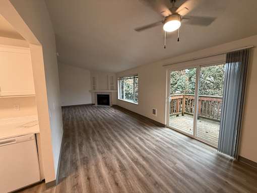 A spacious living room with a ceiling fan and sliding glass doors leading to a deck.