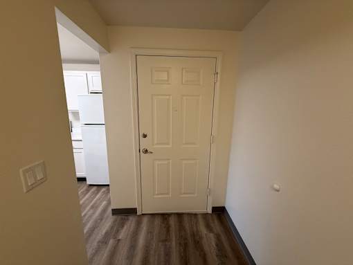 A white door is in a room with a wooden floor.