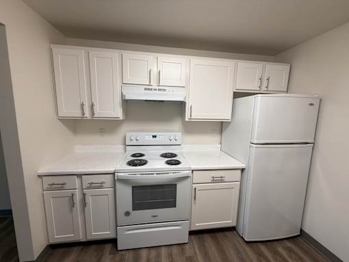 A white kitchen with a stove, oven, and refrigerator.