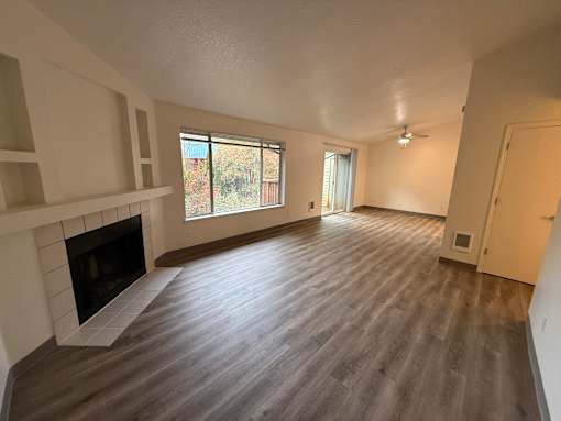 A spacious living room with a fireplace and hardwood flooring.