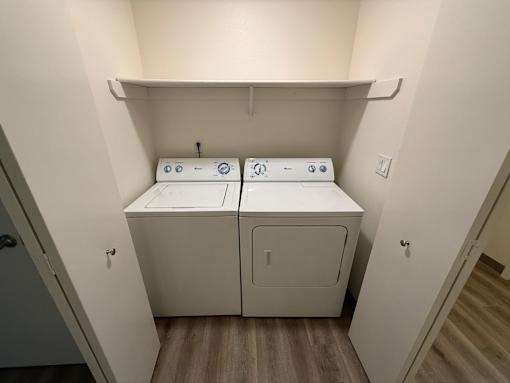 A small laundry room with two washers and a shelf above.