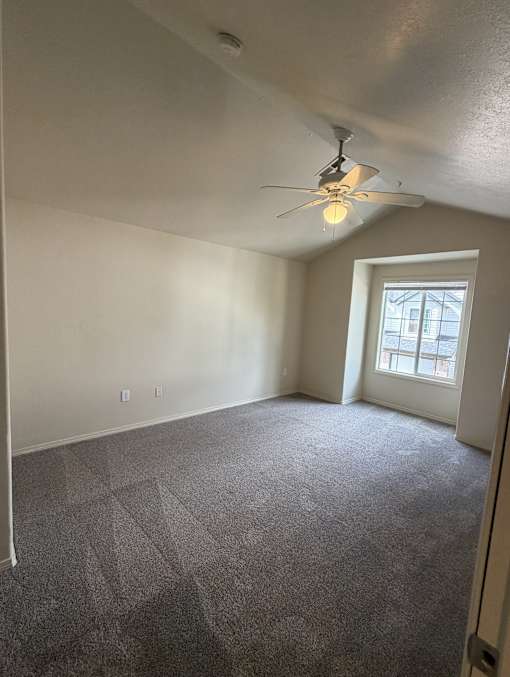 A room with a ceiling fan and a window.