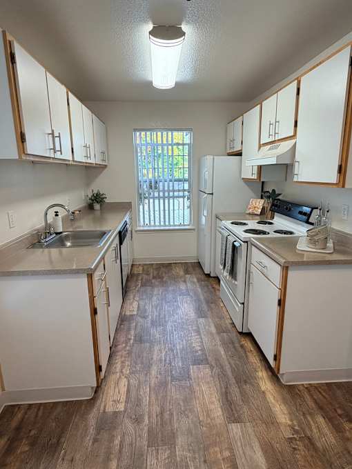 A kitchen with white cabinets and a wooden floor.