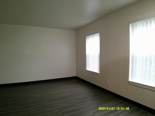 A room with a window and a wooden floor.