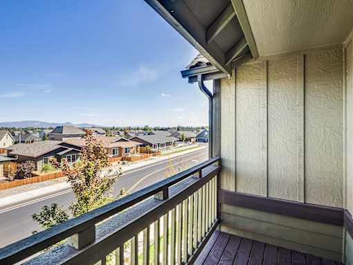 A balcony overlooks a street with houses and trees.
